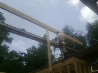 Carpenter setting a ridge beam over a new addition frame — Ice Dam Removal by Roofing Brothers in Central City